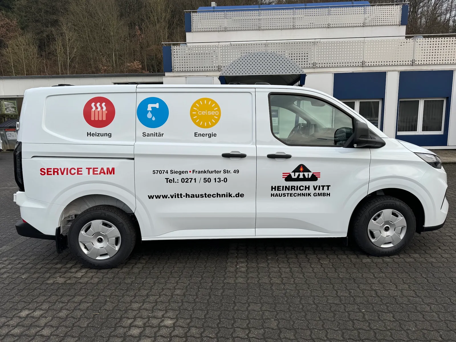 Weißer Servicewagen mit Logo und der Aufschrift Service Team vor dem Firmengebäude
